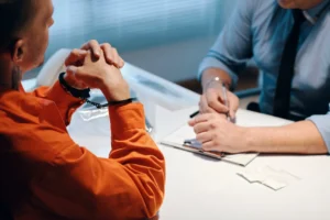 A man in handcuffs being questioned.