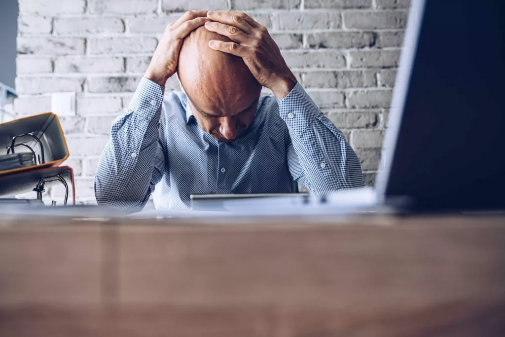 A man sitting at a table, holding his head.