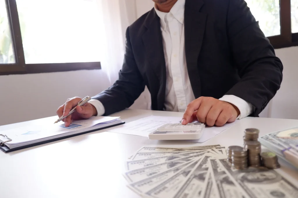 An attorney looking at paperwork, using a calculator with cash.