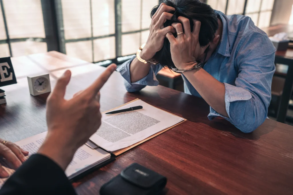 A person in handcuffs, sitting at a desk.