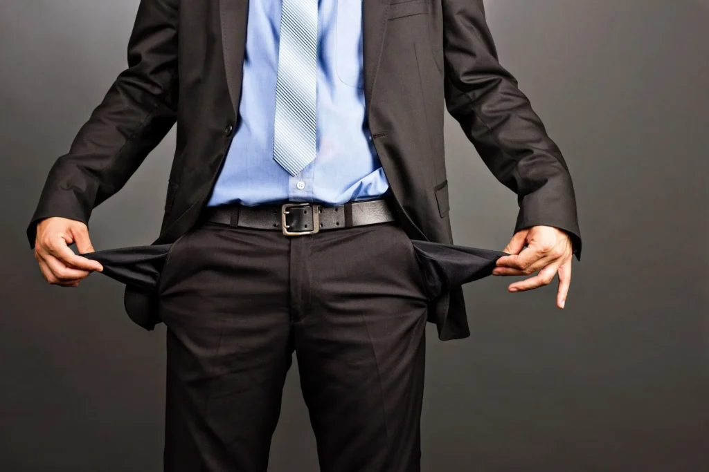 A man in a business suit turning out his pant pockets showing bankruptcy. 